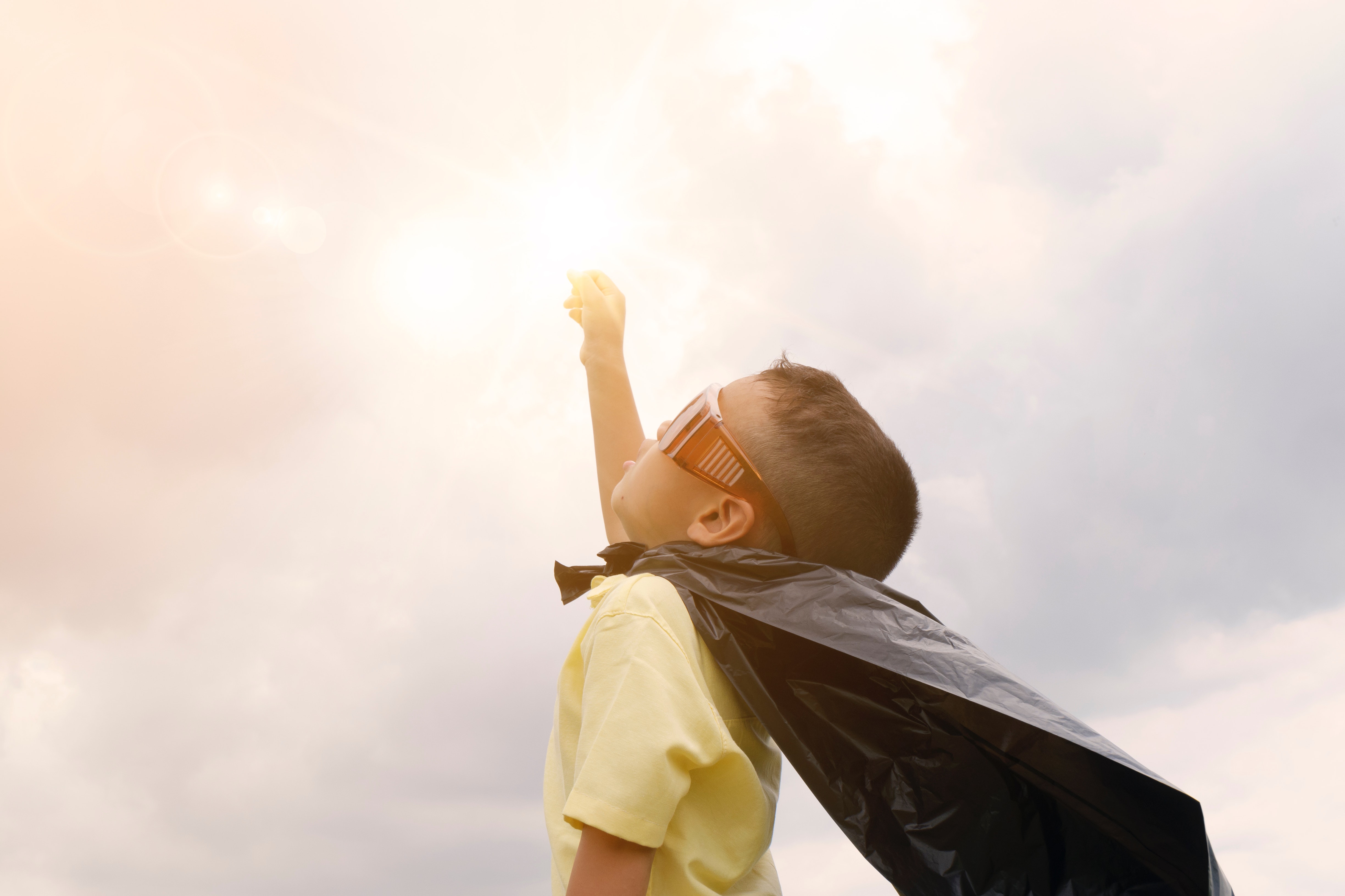 boy raising his hand in a costume of hero gesturing victory